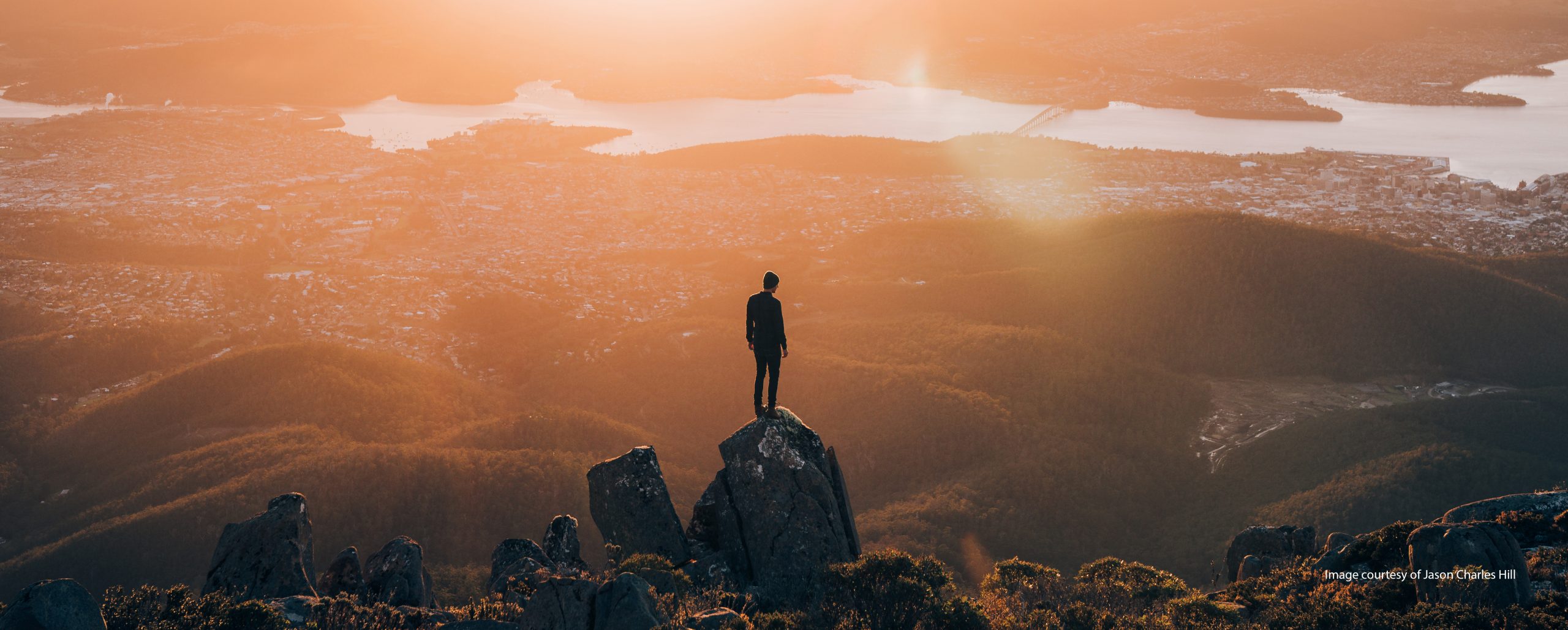 Image of person standing on the summit of kunanyi at sunrise.